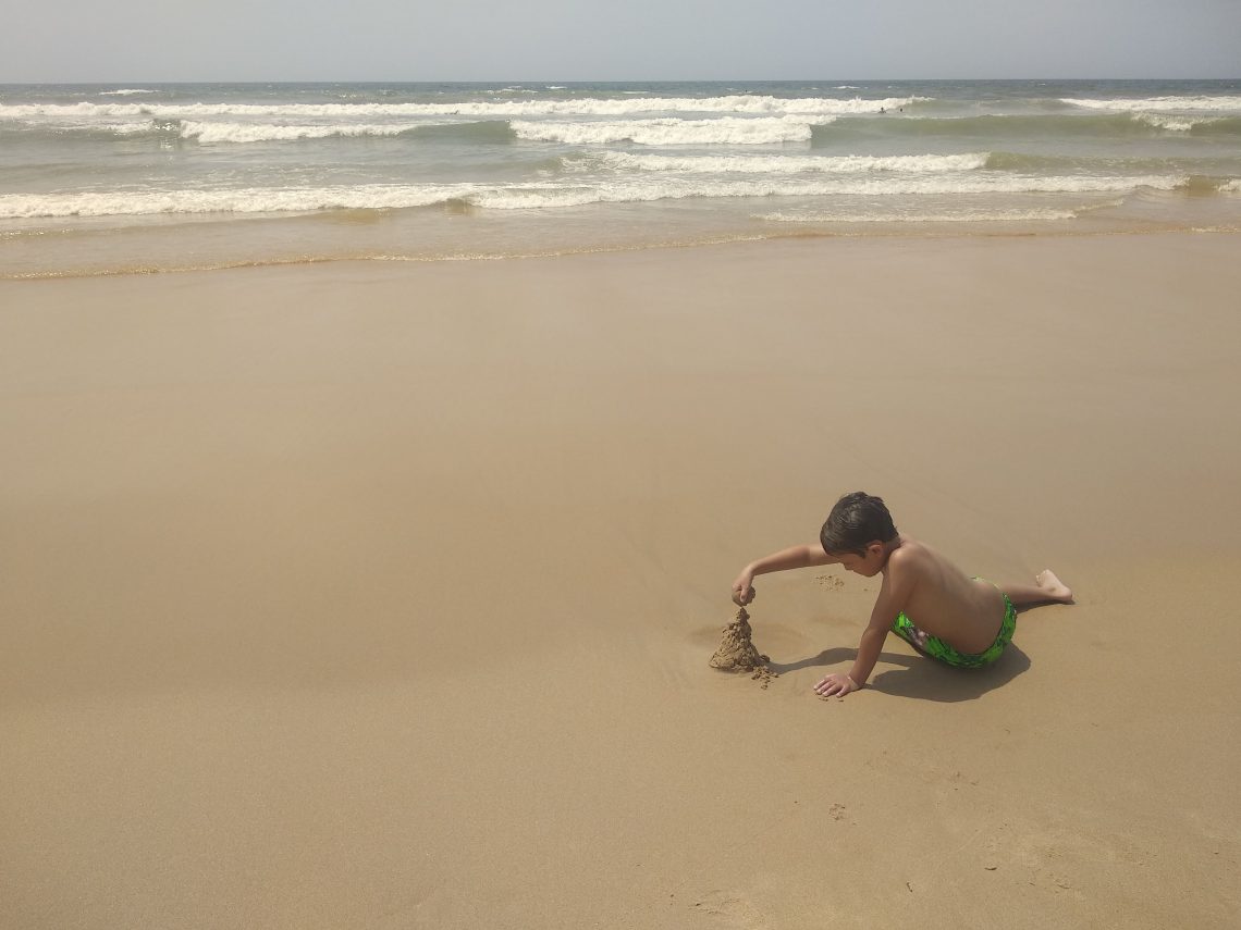 niño en la playa jugando con arena